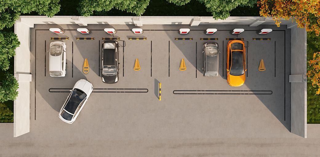 Na zdjęciu widać samochód wjeżdżający na parking. Na niektórych z miejsc postojowych widać automatyczne blokady parkingowe.